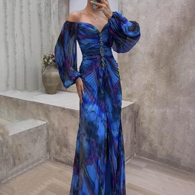 Blue off-shoulder dress with ruched front and floral detailing, worn indoors against a textured wall with a vase on a step.