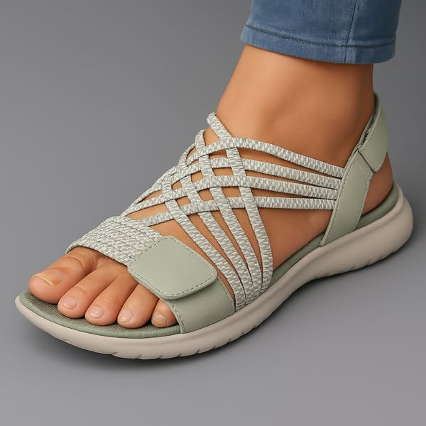 Light green orthopedic comfort sandal with crisscross straps on foot, displayed on gray background.