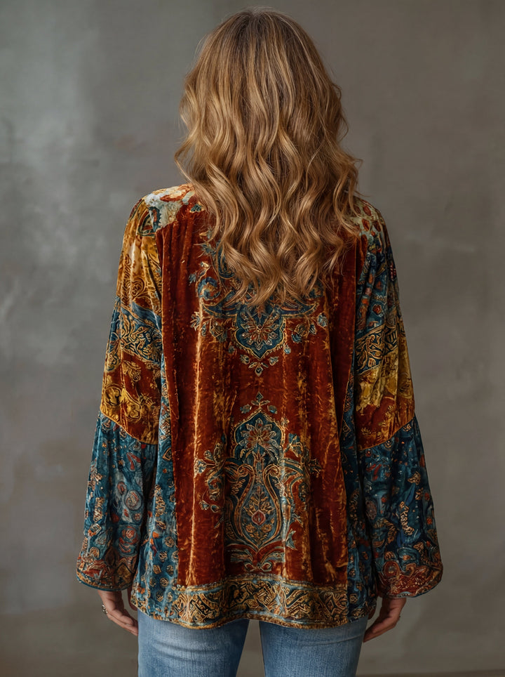 Rear view of colorful embroidered kimono cardigan, showing intricate patterns, worn by a woman with wavy hair in a studio setting.