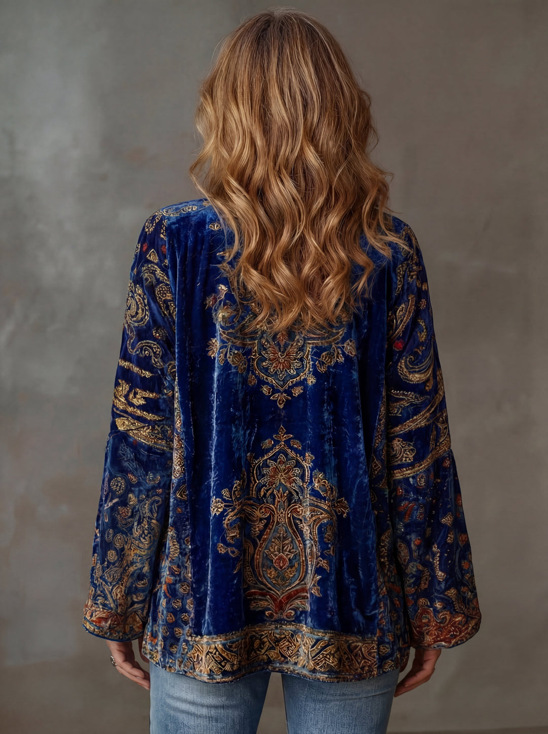 Back view of a blue embroidered kimono cardigan, highlighting detailed patterns, on a woman with flowing hair, studio background.