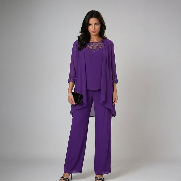 Model in rich purple three-piece set with lace details, holding a black clutch in a studio.