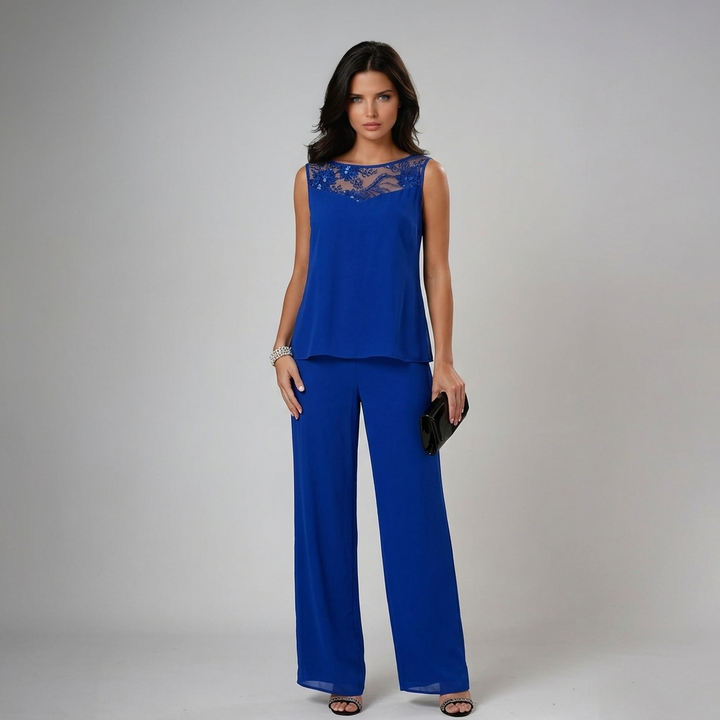 Model in sleeveless blue set with lace detail, holding a clutch in a studio backdrop.