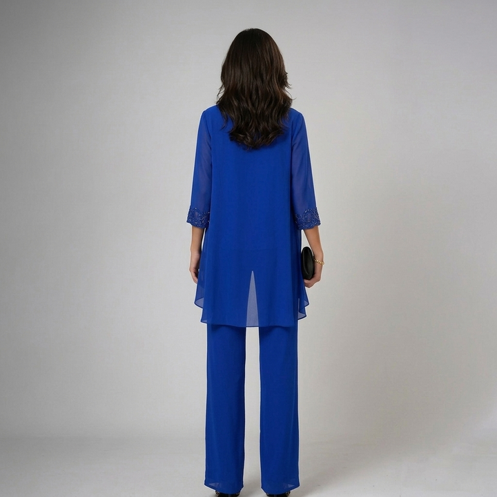 Back view of model in blue set with lace cuffs, holding black clutch in a studio environment.