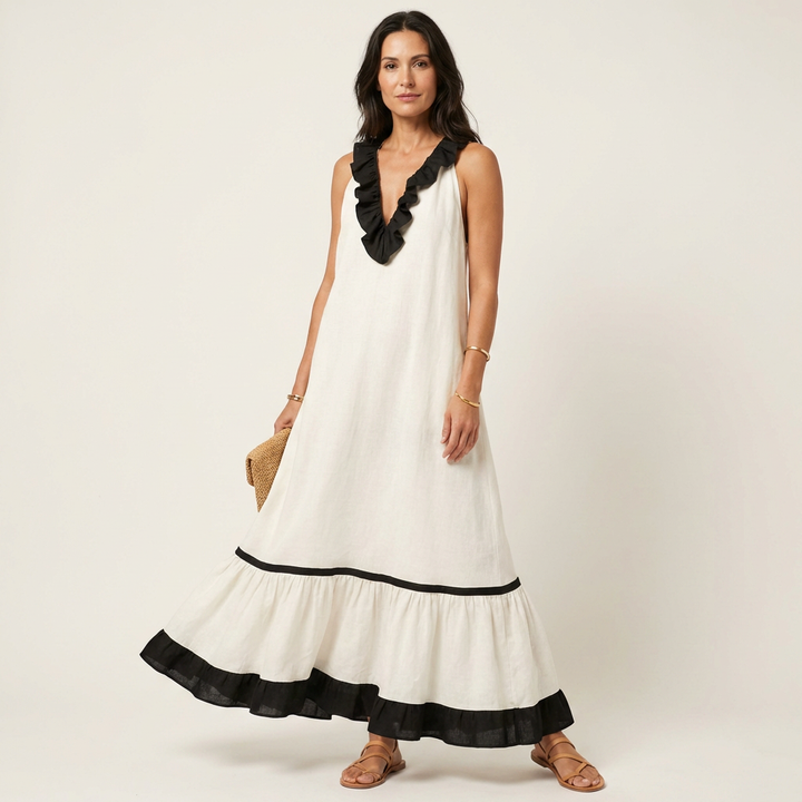 Woman in white sleeveless maxi dress with ruffle-neck and contrast trim, holding bag in studio.