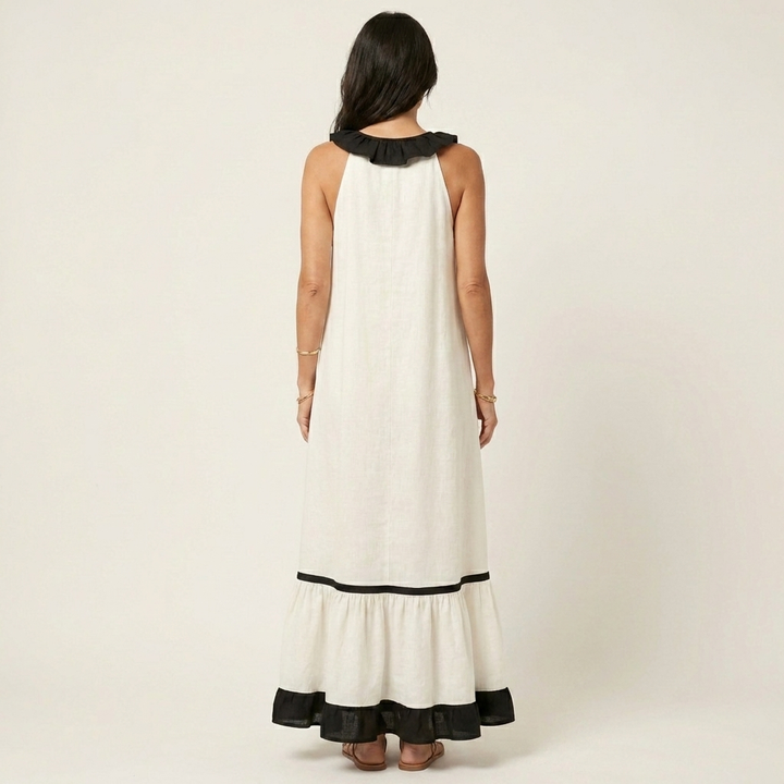 Back view of woman in white sleeveless maxi dress with ruffle-neck and contrast trim in studio.