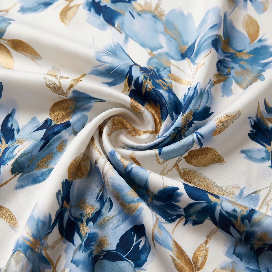 Close-up of a floral fabric featuring blue and gold flowers twisted to show texture in a studio setting.