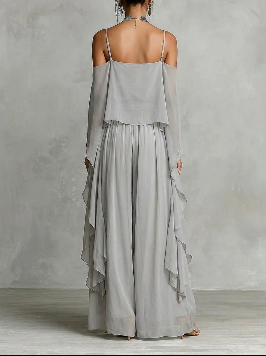 Back view of gray flowy off-shoulder top and skirt set in a studio with gray textured background.
