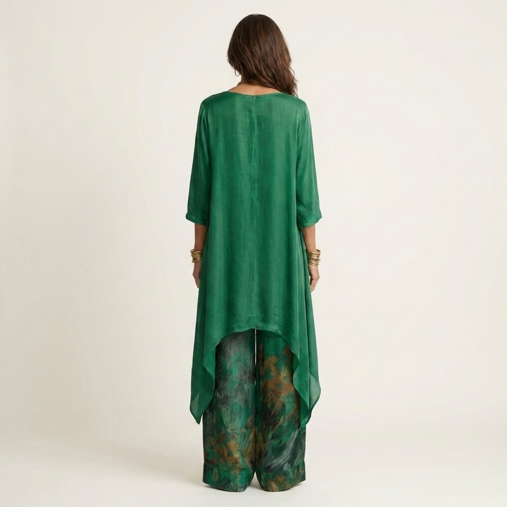 Back view of emerald green elegant set with flowing top and floral wide-leg pants in studio.