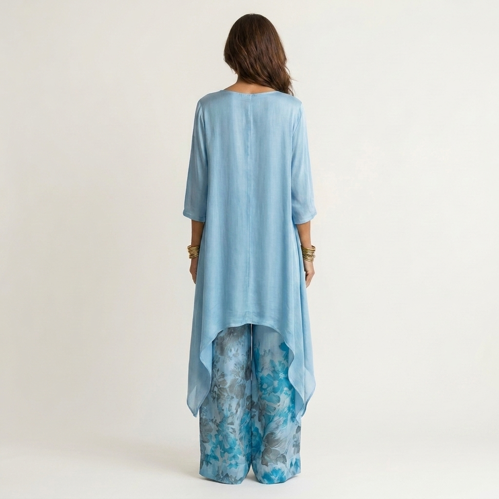 Back view of light blue elegant set with flowing top and floral wide-leg pants in studio.