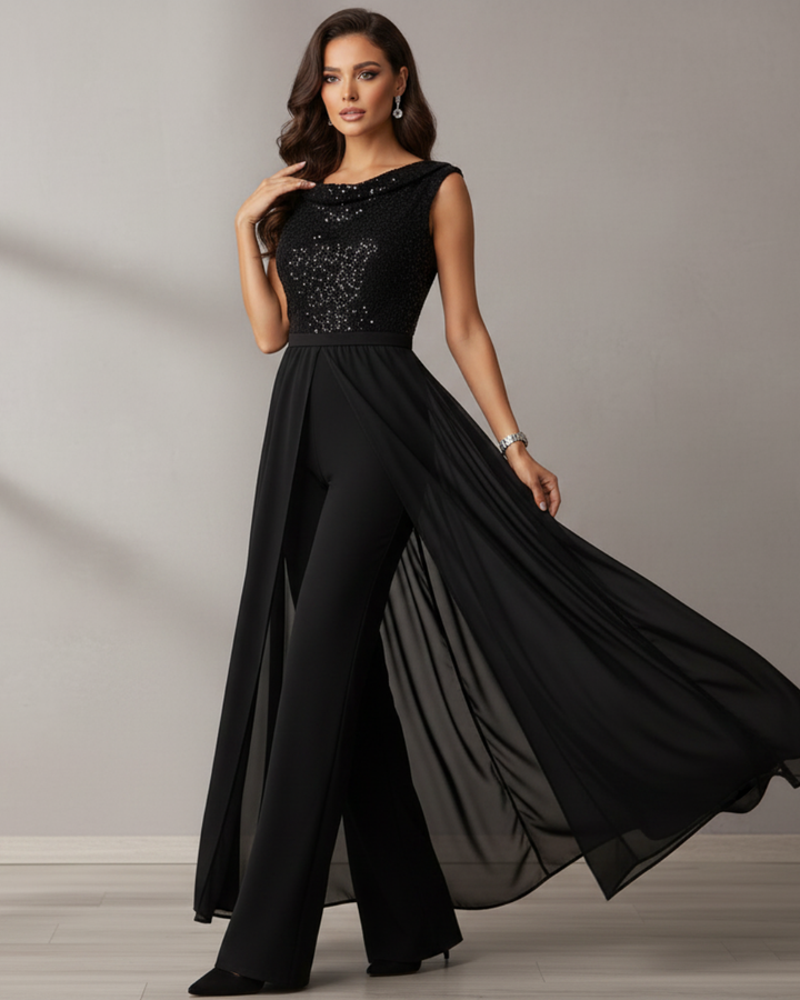 Elegant black jumpsuit with a sequined top and flowing sheer overlay in a studio setting.