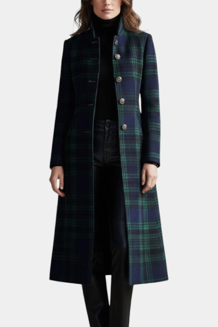 Full front view of a long plaid coat with ornate buttons, worn over a turtleneck and pants, in a studio environment.