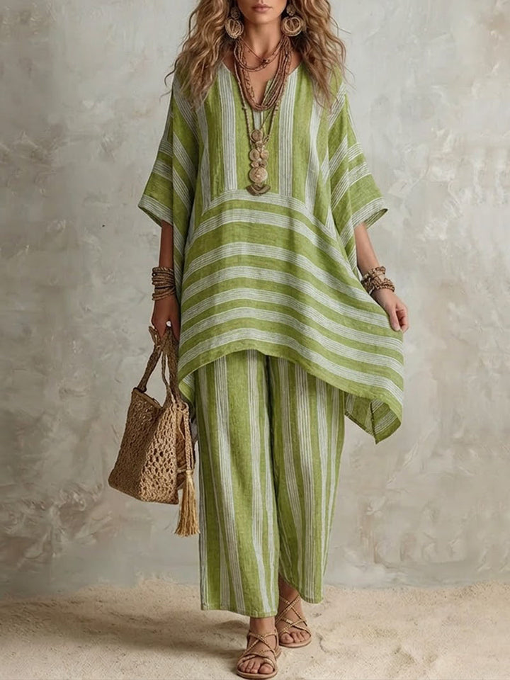 Green and white striped two-piece set with loose top and wide pants, styled with layered necklaces and a woven bag, in a neutral studio setting.