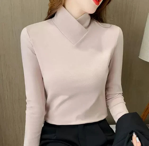 Light pink high-neck sweater with long sleeves, worn indoors against a neutral wall.