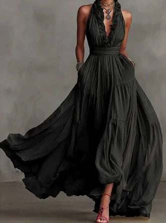 Elegant maxi skirt set in flowing dark fabric, featuring a halter neckline. Model stands in a neutral studio setting.