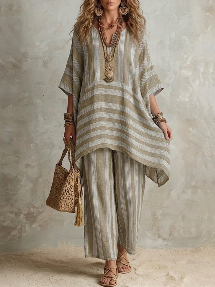 Beige and white striped two-piece set with a relaxed top and wide pants, styled with layered necklaces and a woven bag, in a neutral studio setting.