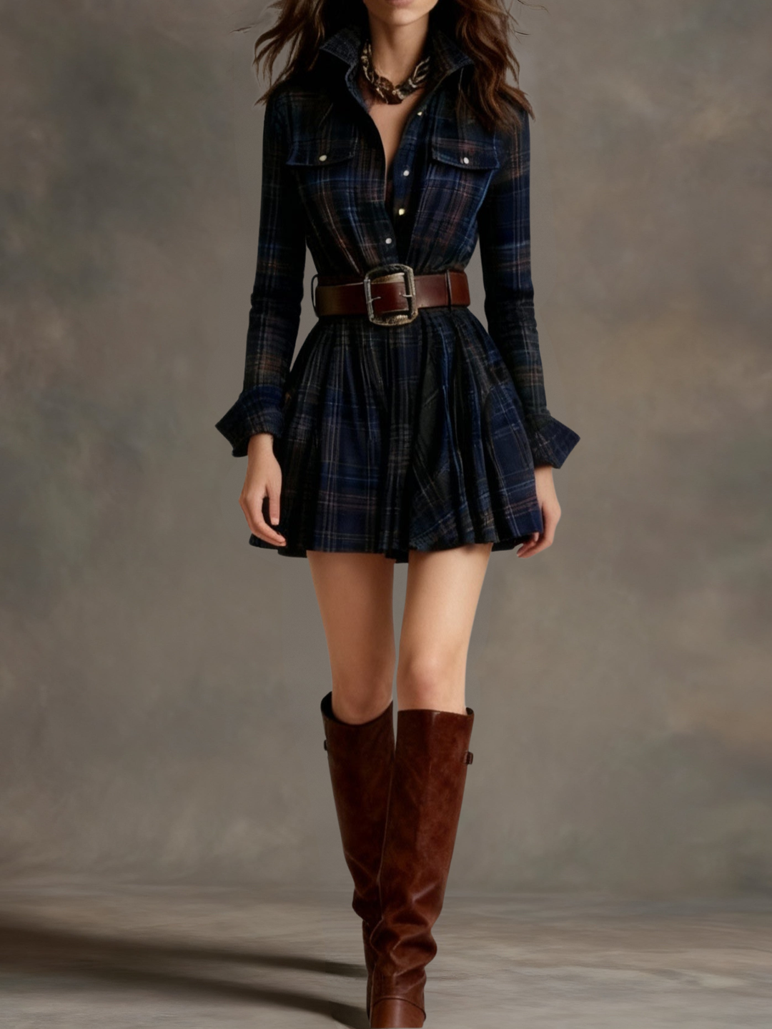 Dark plaid mini dress with a structured belt and knee-high boots styled in a studio setting.