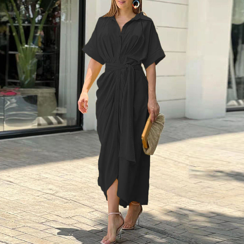Elegant black wrap maxi dress with structured design, worn outside in a sunny urban environment.
