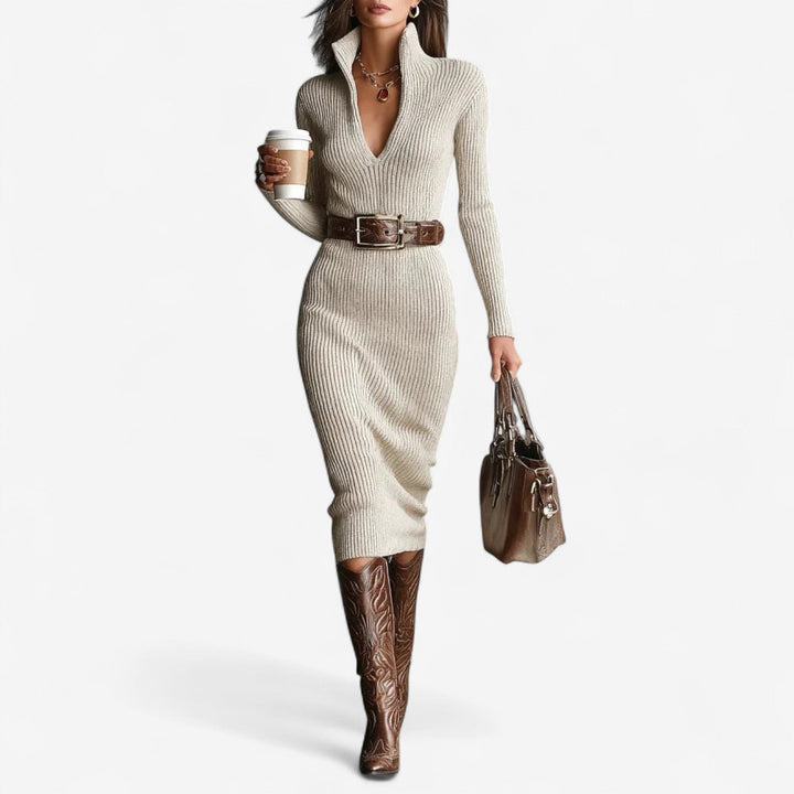 Elegant light-colored ribbed dress with a high collar, belt, and matching boots. Model holds a handbag and coffee, studio background.