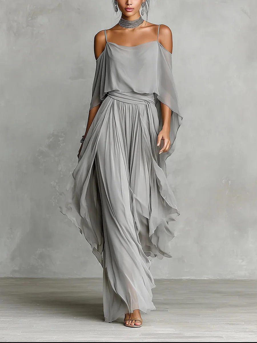 Gray flowy off-shoulder top and skirt set modeled in a studio with gray textured background.
