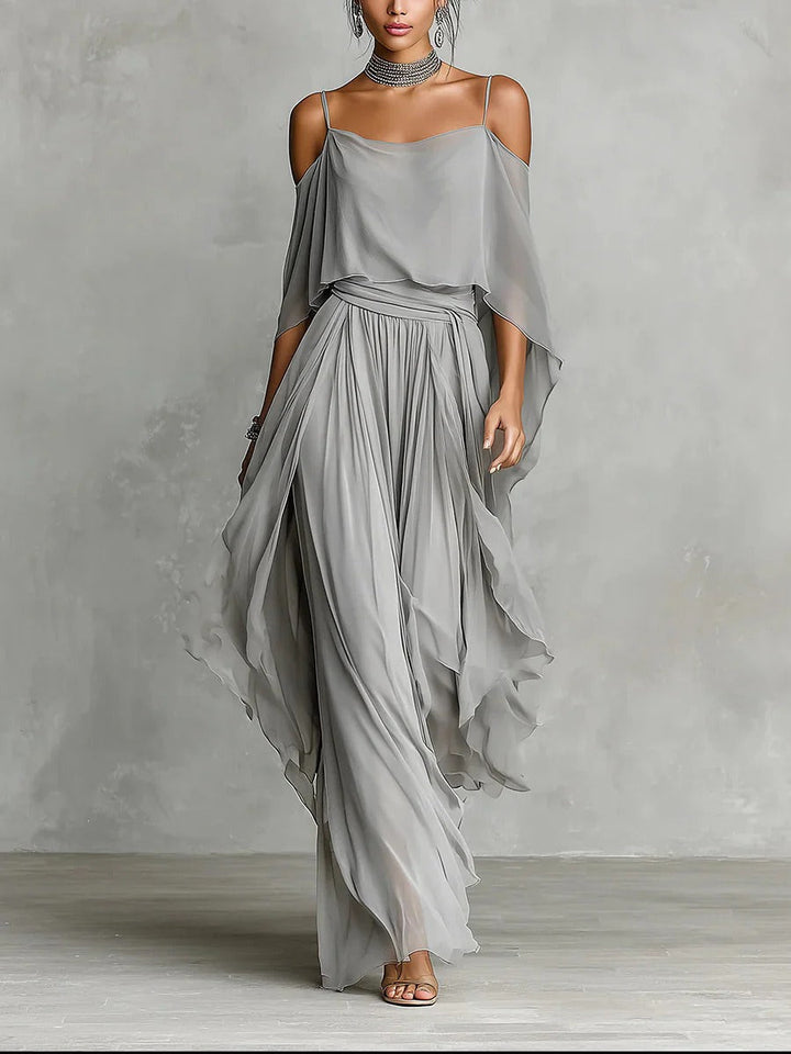 Gray flowy off-shoulder top and skirt set modeled in a studio with gray textured background.