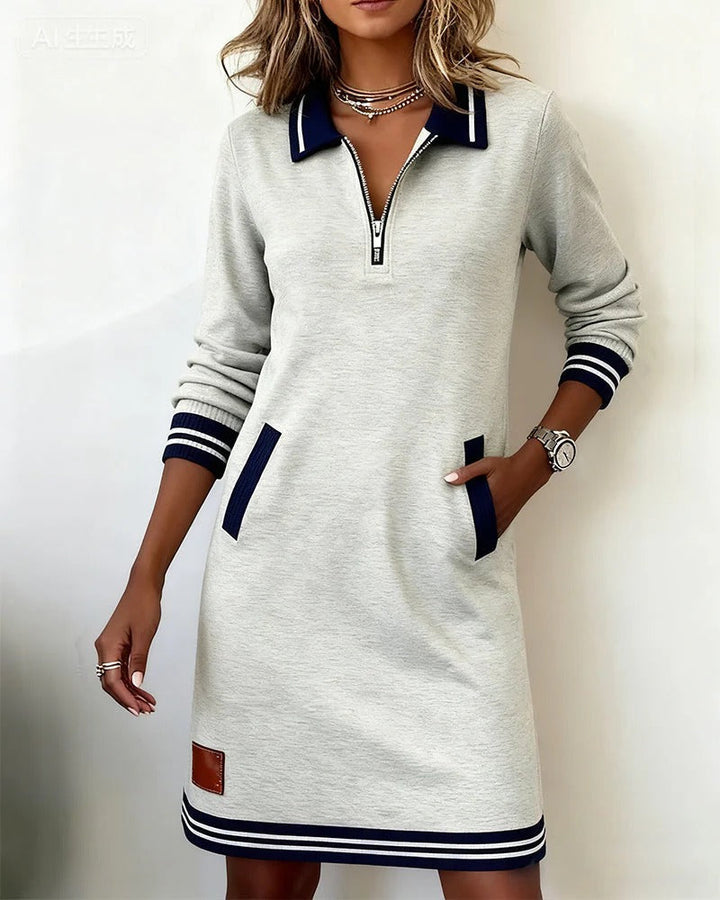 Heather gray dress with a zip front, navy accents, and side pockets, featured in a bright setting.
