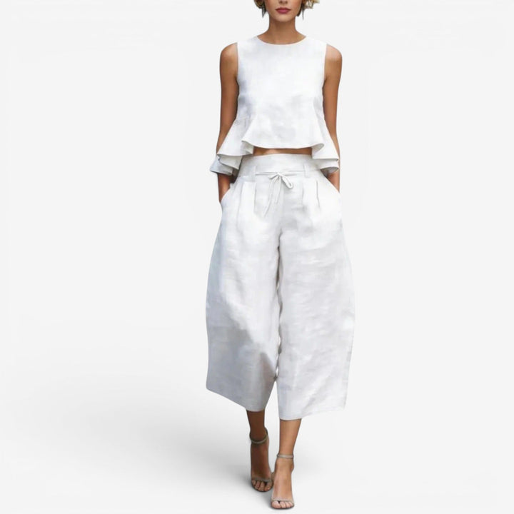 White two-piece set featuring a sleeveless top and wide-leg pants in a studio setting.