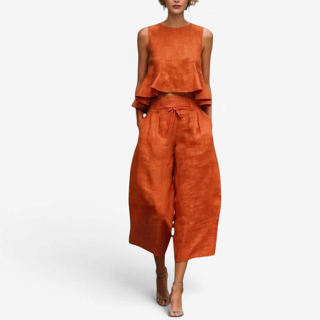 Orange two-piece set with sleeveless top and wide-leg pants in a studio setting.