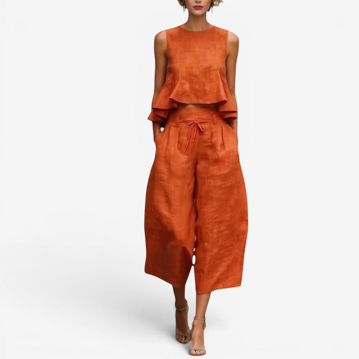 Orange two-piece set with sleeveless top and wide-leg pants in a studio setting.