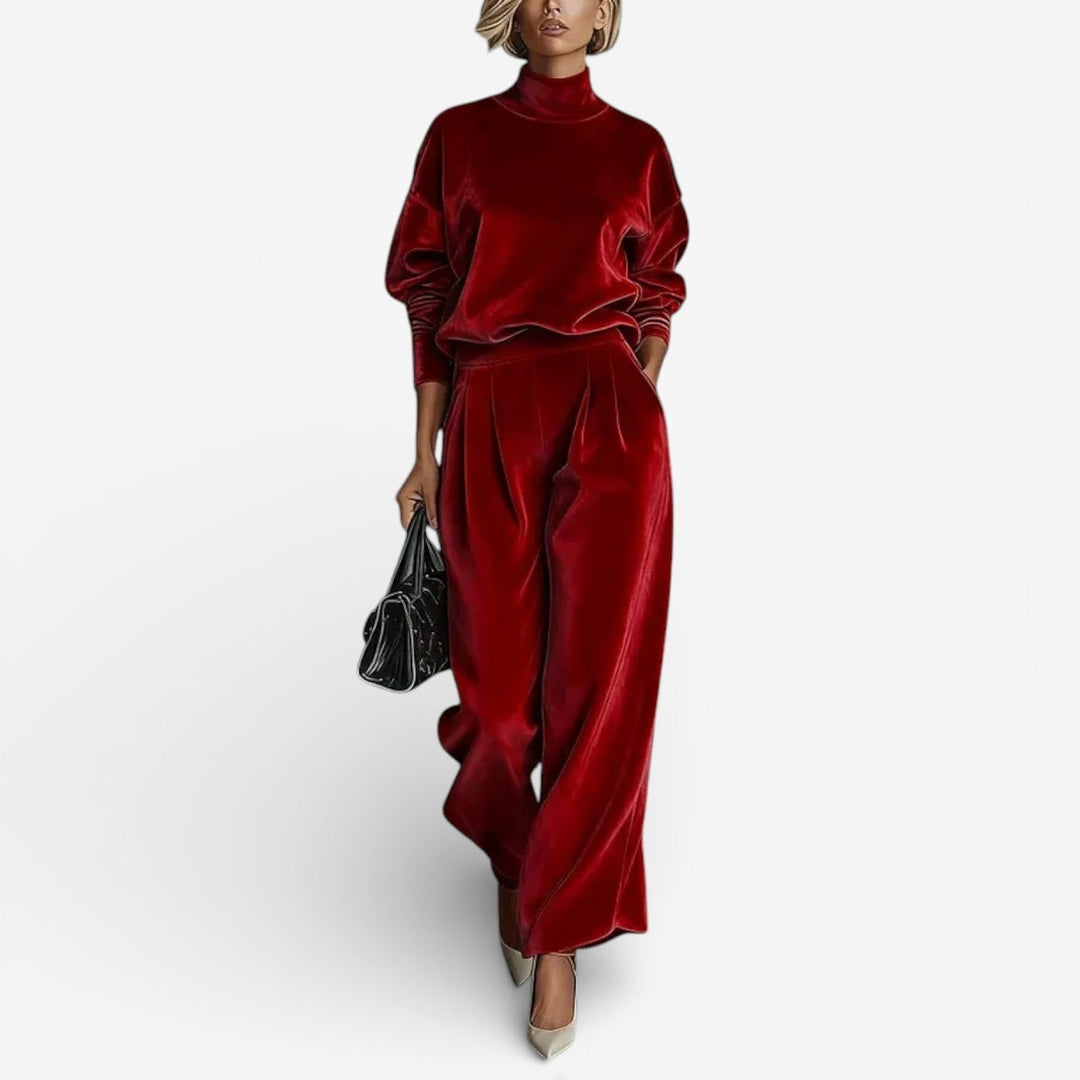 Model in deep red contemporary set featuring a turtleneck and wide-leg pants, carrying a black bag, on white background.