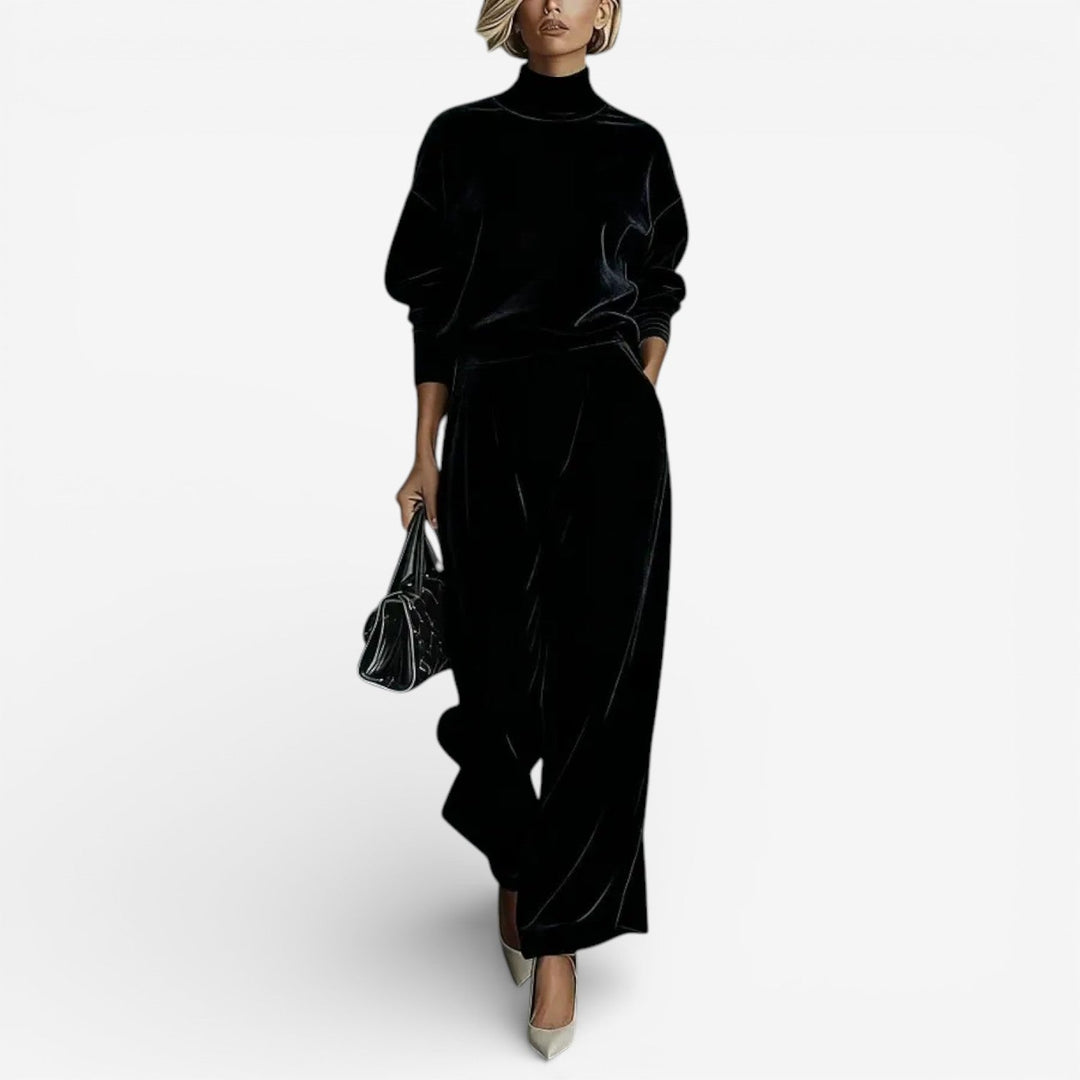 Model wearing black contemporary set with turtleneck and wide-leg pants, holding a black bag, against a white background.