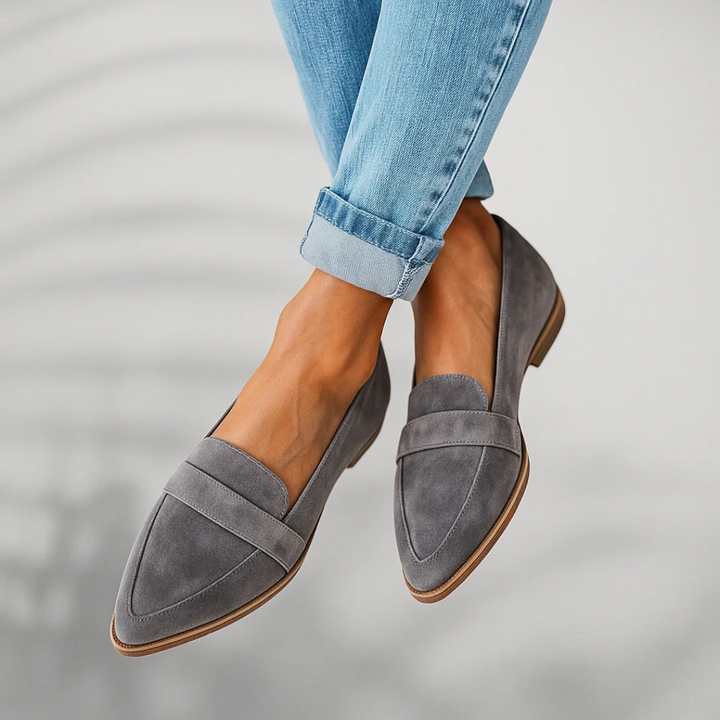 Person wearing gray orthopedic moccasins with cuffed light blue jeans in a well-lit room.