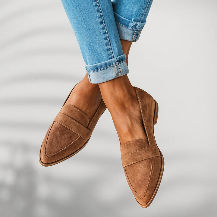 Person in brown orthopedic moccasins with cuffed light blue jeans in a bright indoor setting.