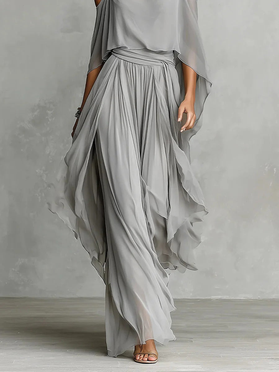 Gray flowy skirt with off-shoulder top modeled in a studio against a gray textured backdrop.