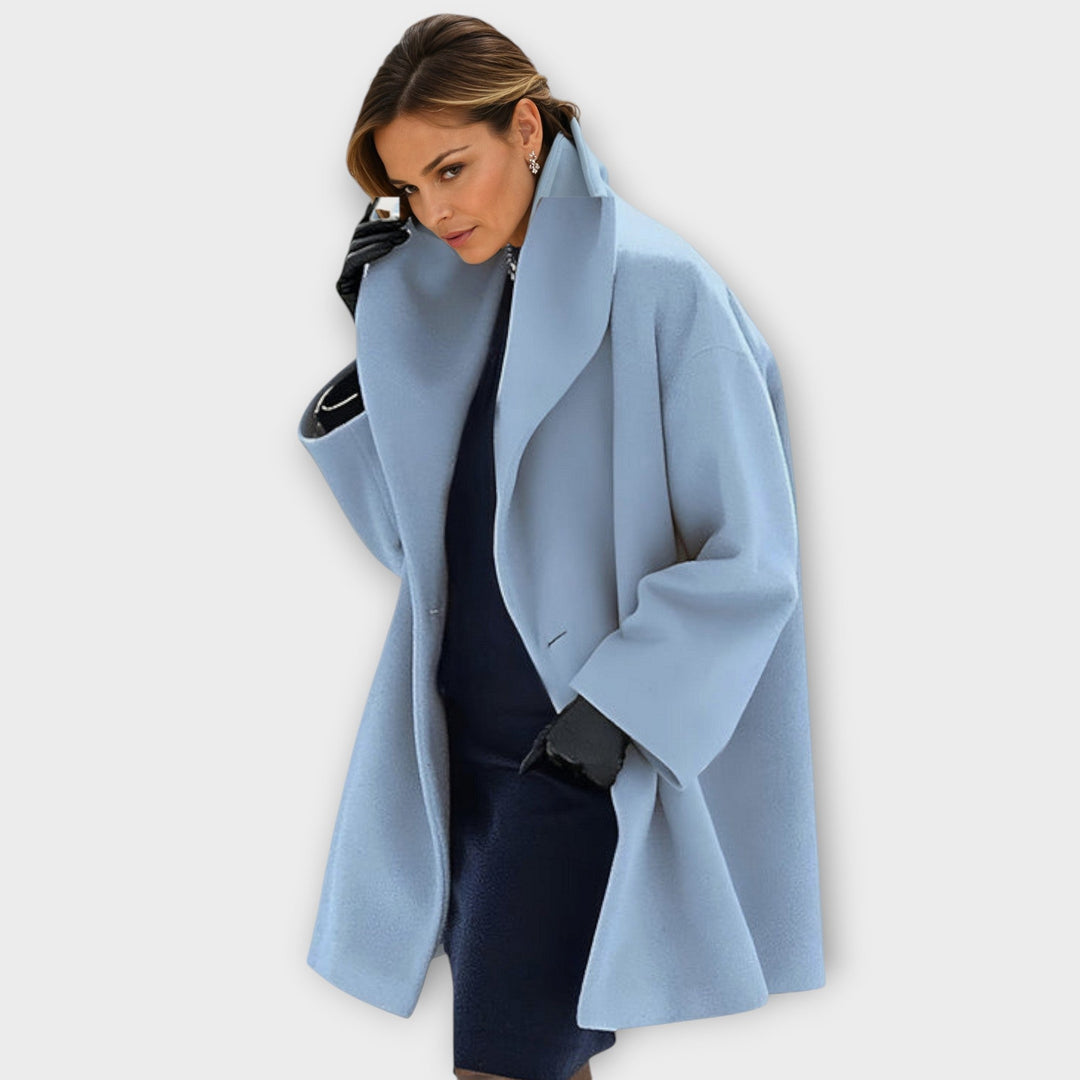 Woman wearing a light blue hooded coat with wide lapels in a studio setting.