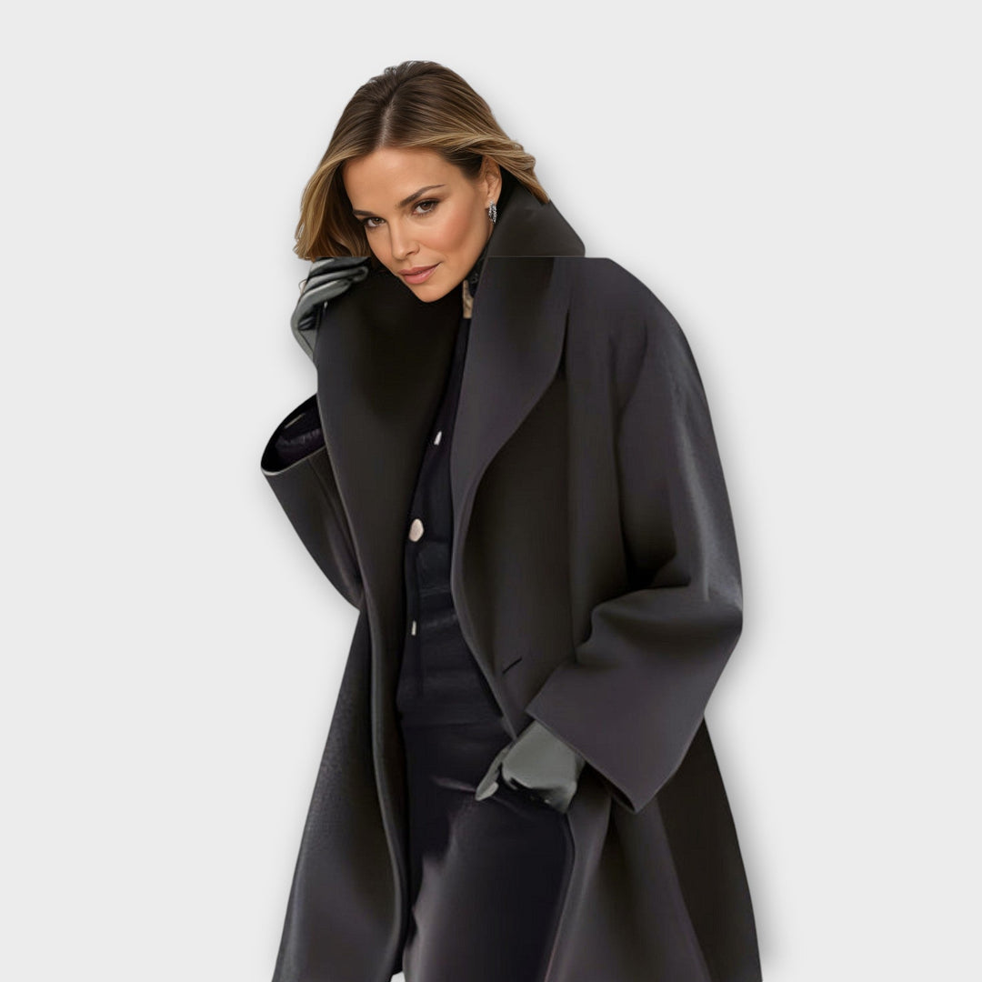 Woman in a dark charcoal hooded coat with wide lapels, posed in a studio.
