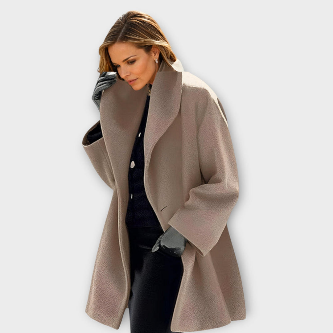 Woman wearing a soft brown hooded coat with wide lapels in a plain studio setting.