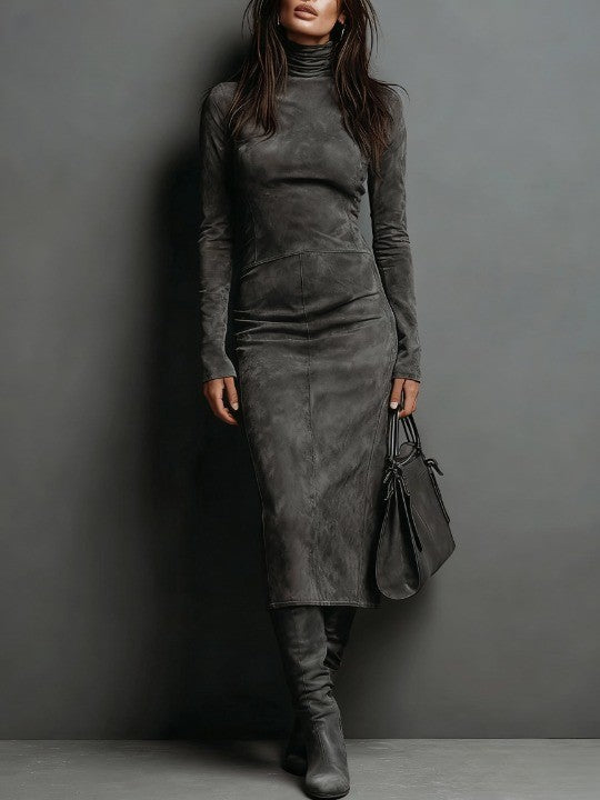 Model in a charcoal suede maxi dress with long sleeves, accompanied by a handbag and boots, against a simple studio backdrop.