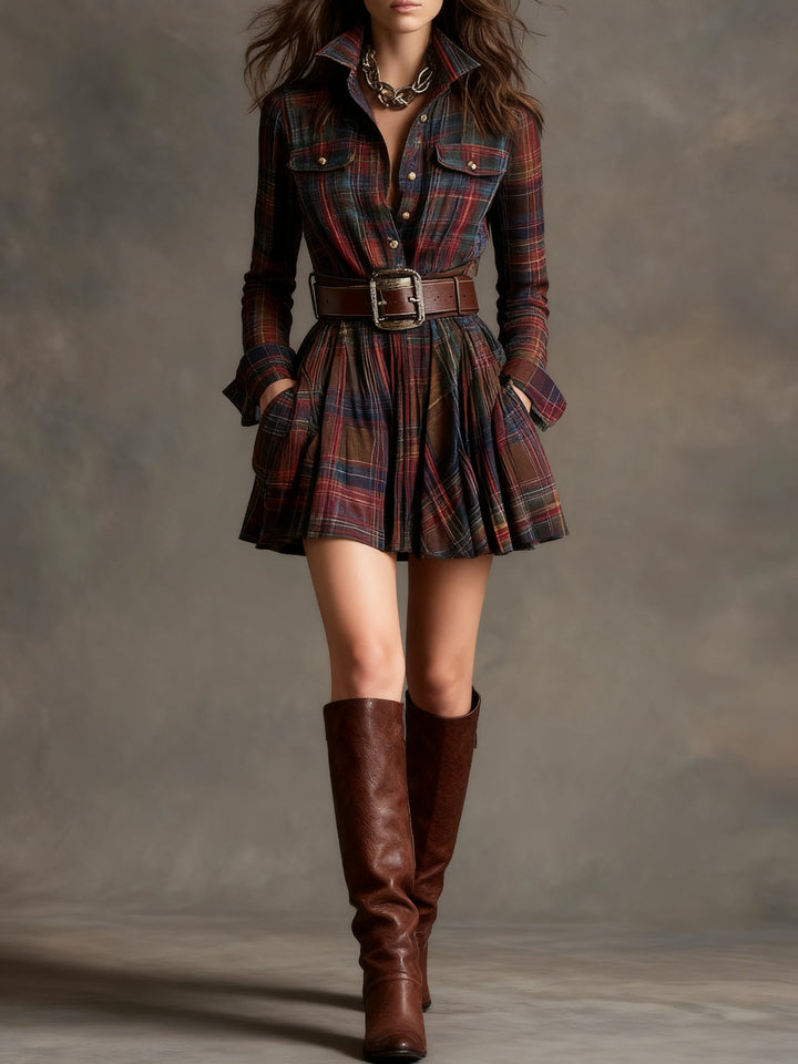 Model in plaid vintage mini dress with a structured belt and knee-high boots in a studio setting.