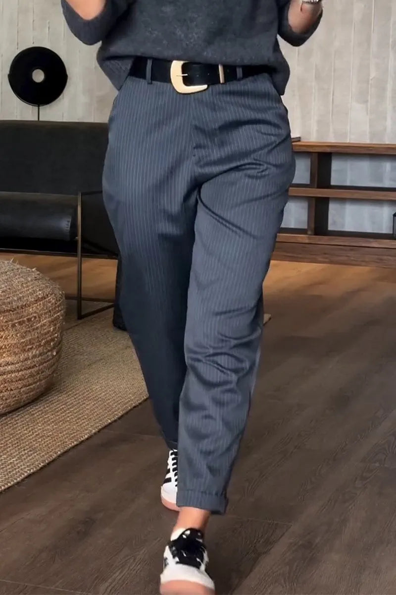 Pinstripe tailored pants in a modern indoor setting with wooden floors, paired with a black belt and casual sneakers.