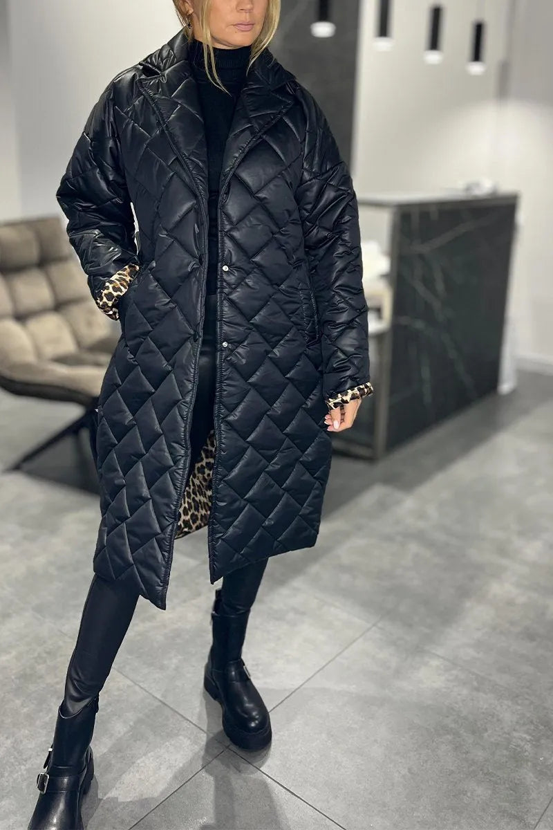 Model in a black quilted coat with leopard print lining, standing in a modern indoor setting with gray flooring and a cushioned chair.