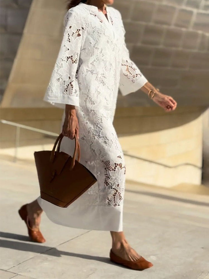 Woman in white cutout dress holding brown handbag, walking briskly in a smooth, modern outdoor setting.