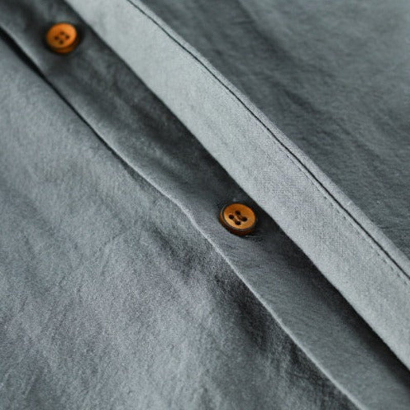 Close-up of gray fabric shirt with brown buttons, highlighting the smooth texture.