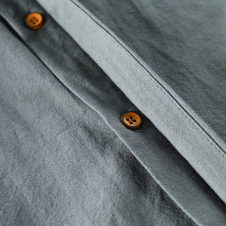 Close-up of gray fabric shirt with brown buttons, highlighting the smooth texture.