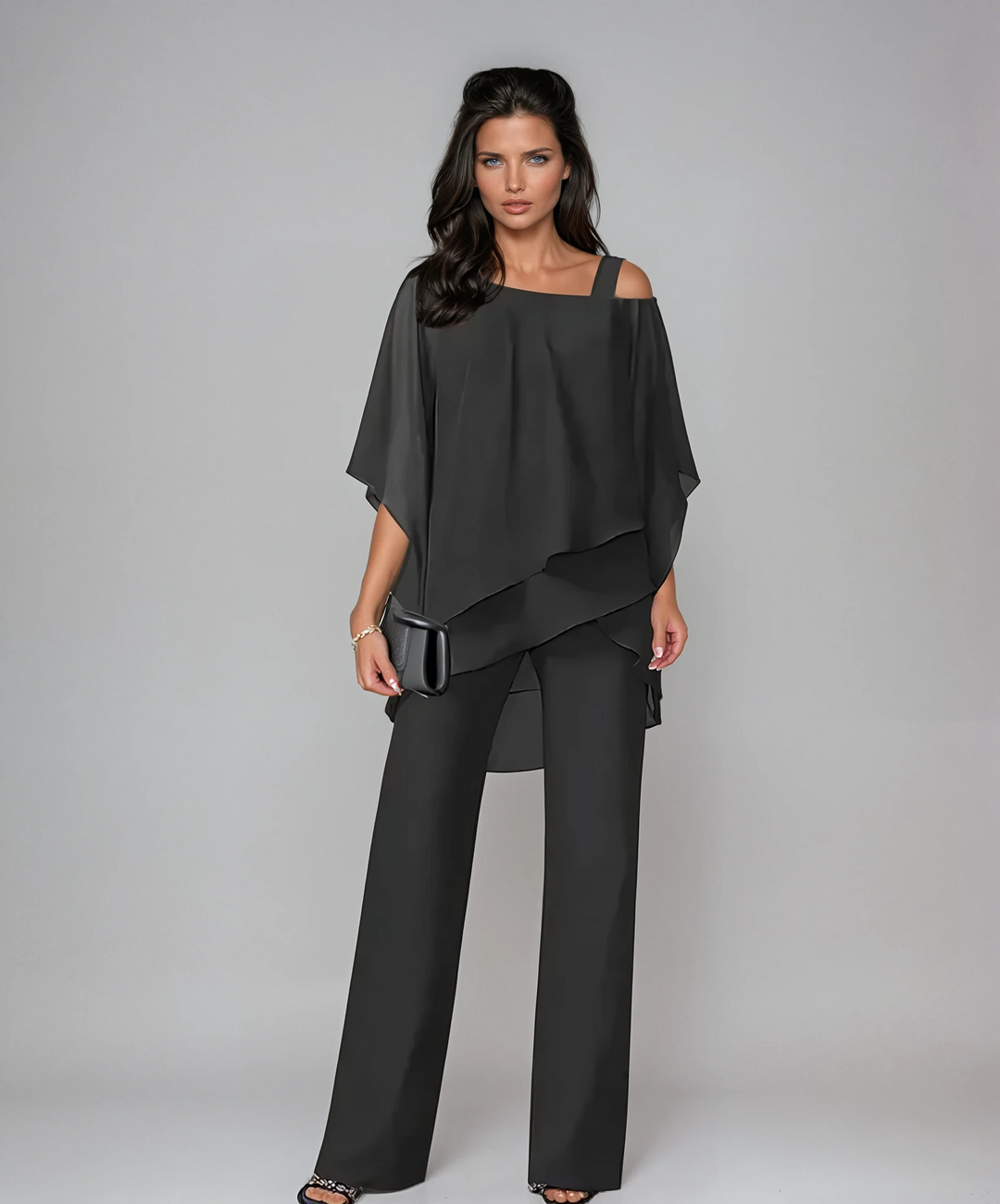 Model wearing black two-piece layered set with a black clutch in a studio backdrop.