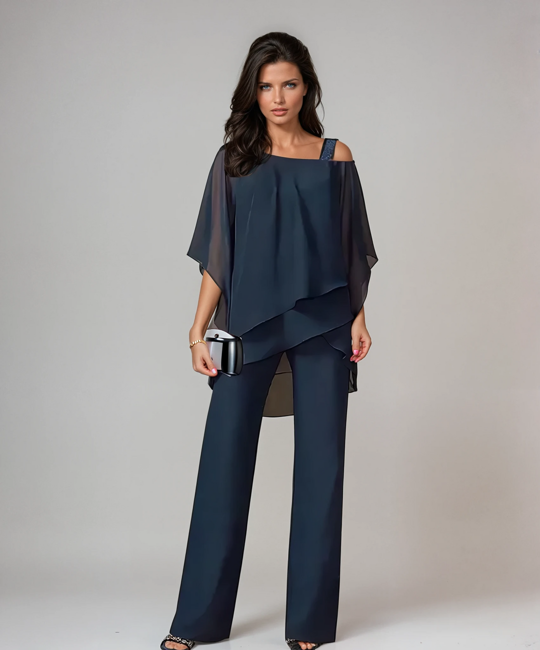 Woman dressed in navy blue two-piece layered set with a metallic clutch in a studio setting.