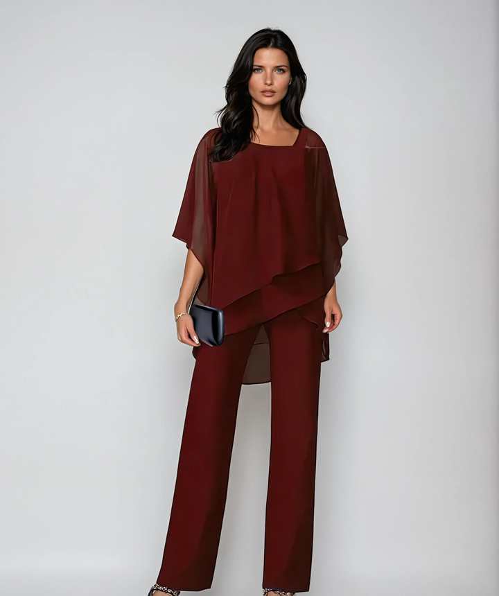 Model in dark red two-piece layered set with a black clutch against a studio background.