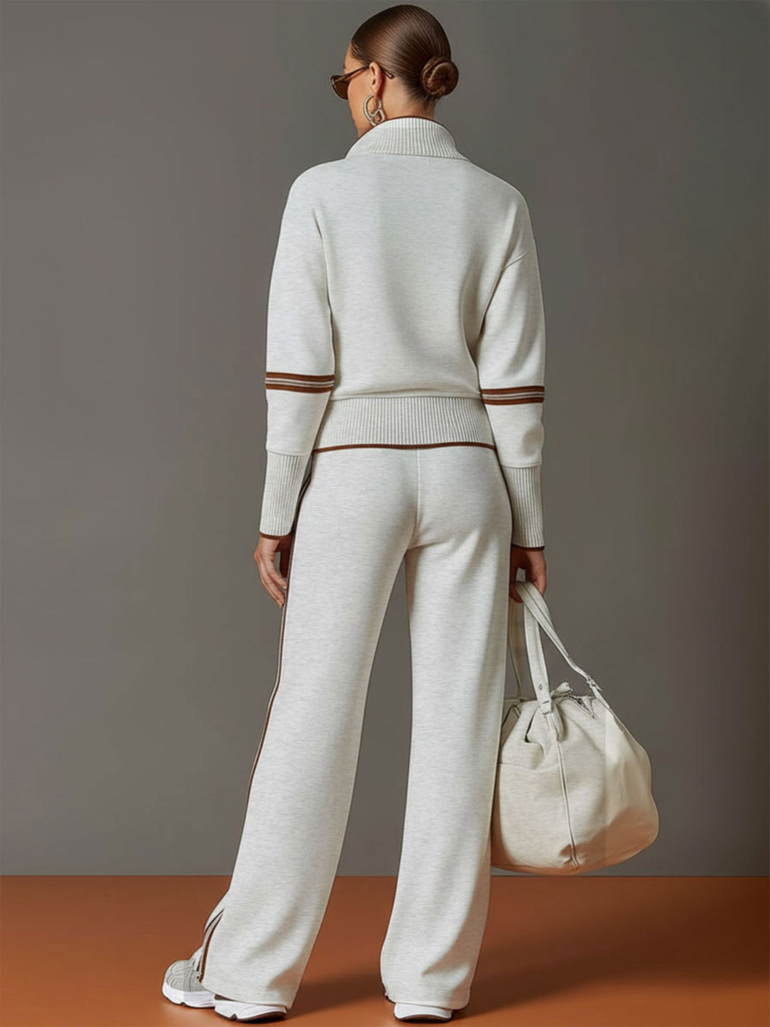 Back view of matching lounge set in light gray with contrast stripes, paired with white sneakers and a bag in a studio setting.