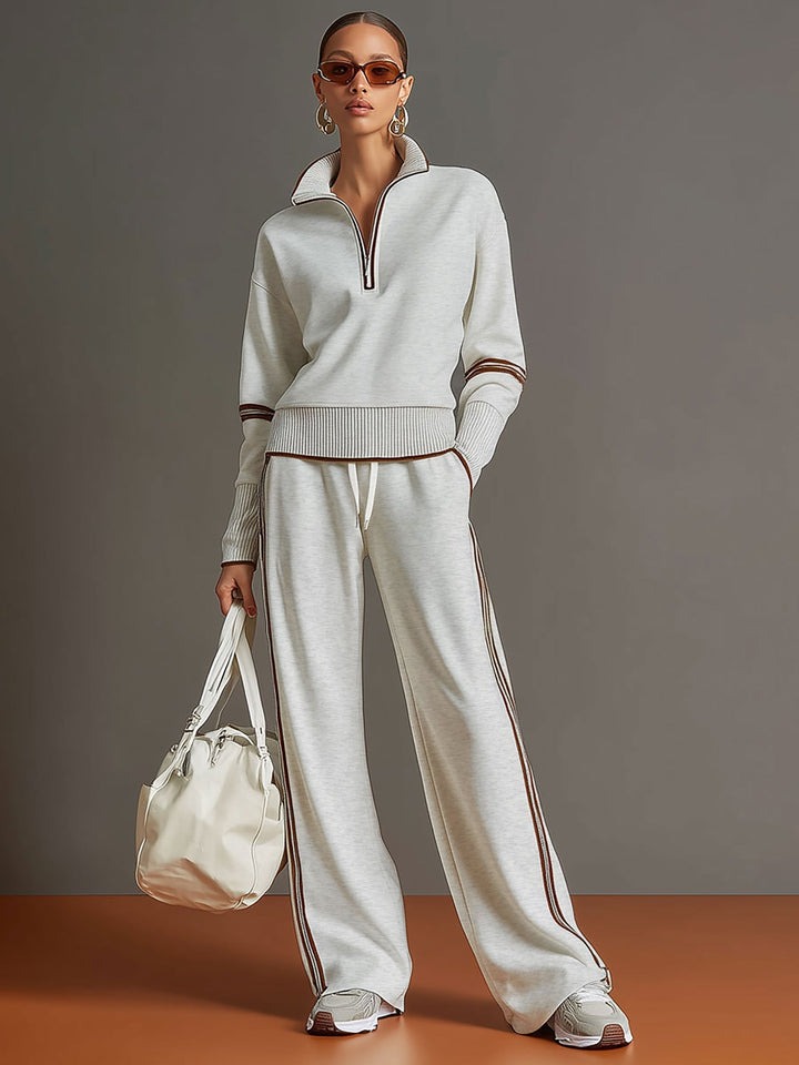 Effortless matching lounge set in light gray with contrast stripes, styled with white sneakers and a bag in a studio setting.