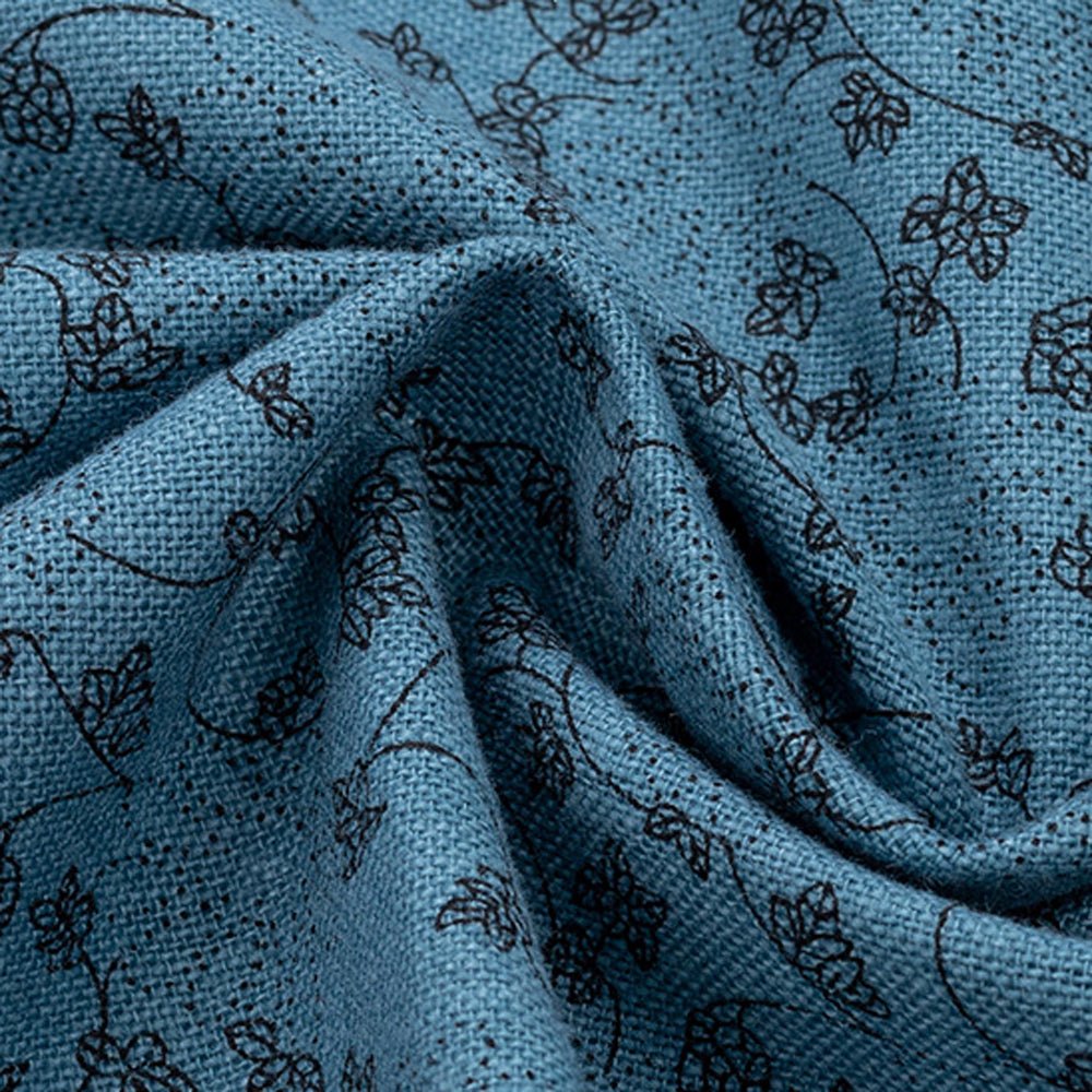 Close-up of blue fabric with dark floral patterns, showcasing its texture.