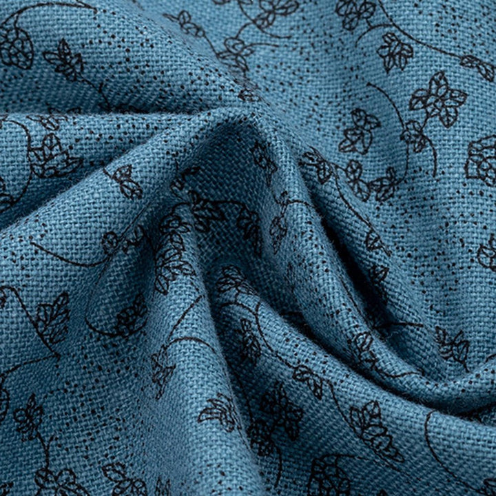 Close-up of blue fabric with dark floral patterns, showcasing its texture.